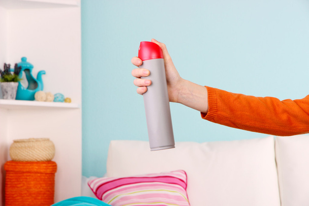 Sprayed air freshener in hand on home interior background - Photo, image