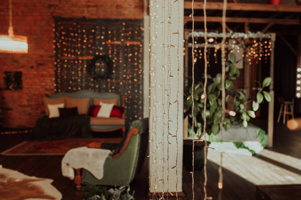increíble interior de Navidad espacioso y ecológico con madera oscura, muebles verdes, hermosos árboles de Navidad elegantes y muchas bombillas y luces - Foto, imagen