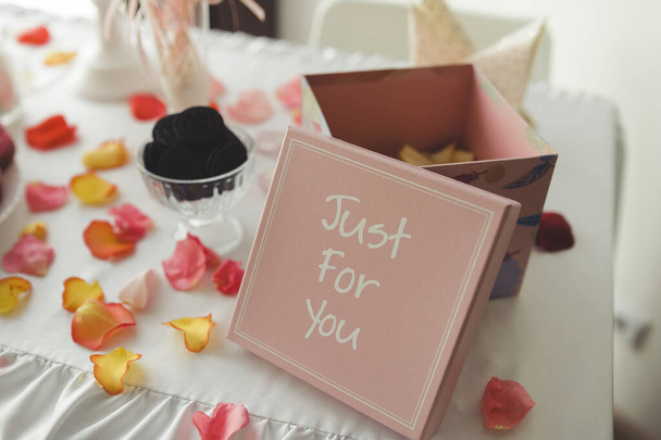 розовая подарочная коробка с надписью для печенья на белом столе с праздничным декором для девочек в розовых цветах - Фото, изображение