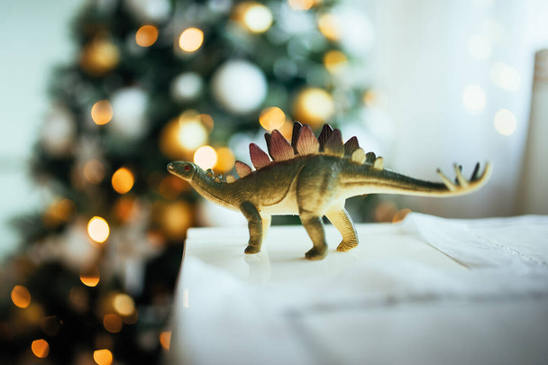 καουτσούκ ρεαλιστικό παιχνίδι δεινόσαυρος σε χριστουγεννιάτικα φώτα γιρλάντα - Φωτογραφία, εικόνα