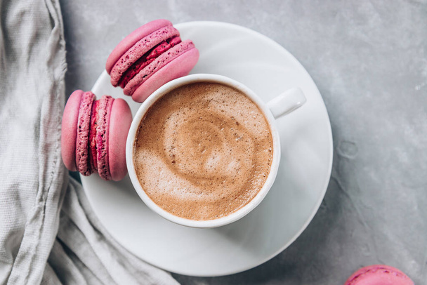  Cup of coffee and small macaroon cakes on gray concrete background, top view. High quality photo - Fotoğraf, Görsel