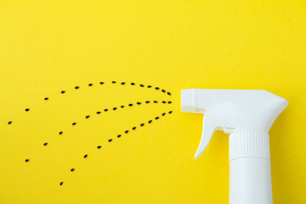 Closeup of white spray  bottle on yellow background with spraying line from black saseme seeds, Spraying water or planting concept. - Photo, Image