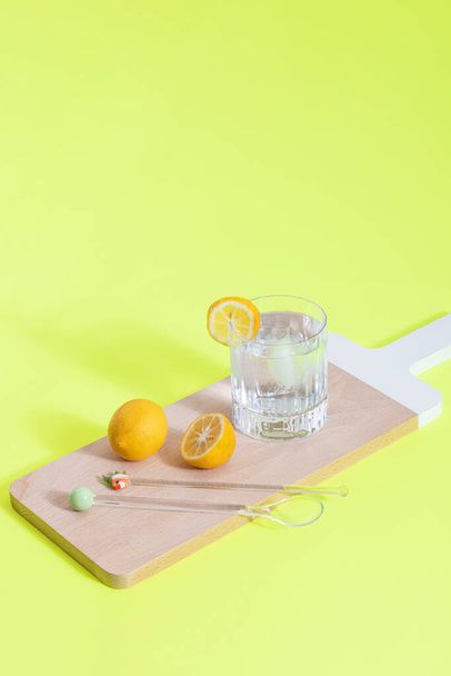 Eiswasser & Zitronen auf Holzoberfläche und neongrünem Hintergrund. - Foto, Bild