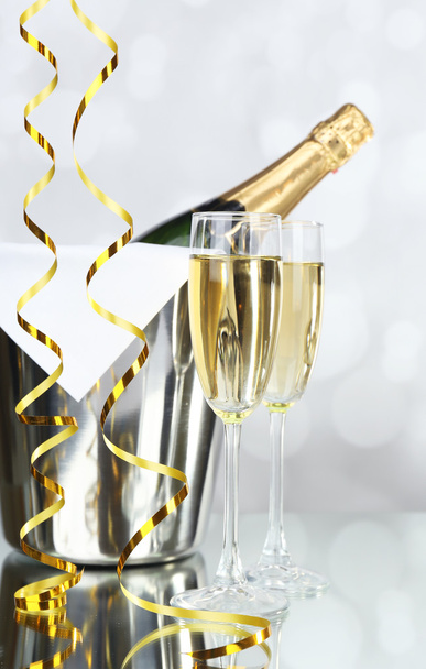 Glasses of champagne and bottle in pail on light background - Valokuva, kuva
