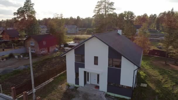 Aerial top view of new modern residential house cottage in a nice neighborhood. Roof made of soft tiles. A fence is being built around the house. Trees and lawn grow on the land - Footage, Video