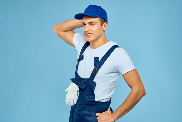 Робочий чоловік в уніформі рукавичок навантажувач відтворює послугу синього фону
 - Фото, зображення