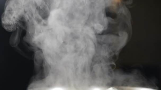 Brillant blanc vapeur se lève de Pan dans la cuisine tourné sur fond noir. Fumée, vapeur, brouillard nuages en mouvement isolés. La vapeur blanche monte sur la casserole. Au ralenti. Full hd - Séquence, vidéo