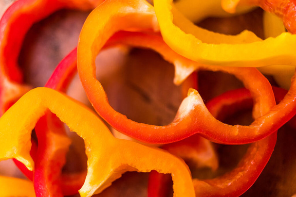 Krájená oranžová, červená a žlutá paprika na dřevěném stole - Fotografie, Obrázek