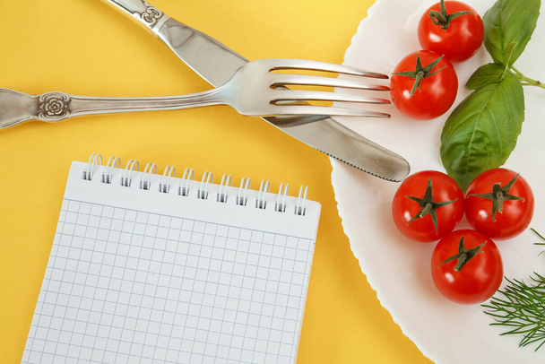 Chery tomatoes on a plate with basil and cutlery. Notebook for recording and counting calories diet food - 写真・画像