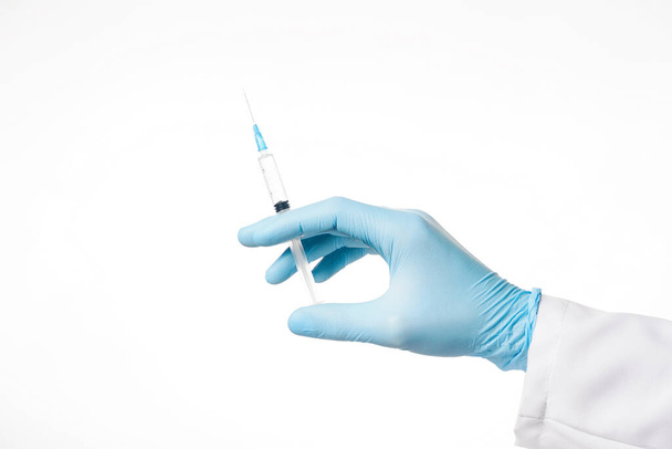 Close up hand in blue glove holding syringe isolated on white background - Фото, изображение