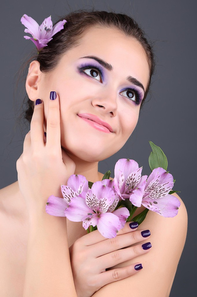 Beautiful young woman with flowers on gray background - Zdjęcie, obraz