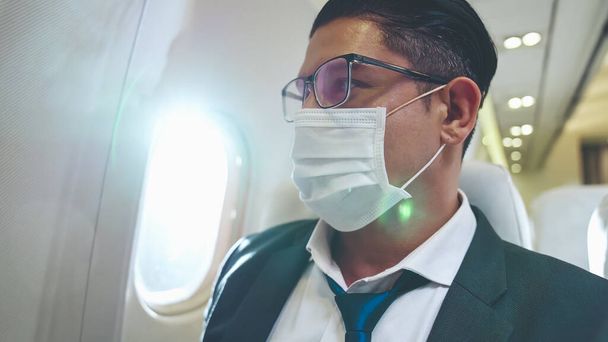 Podróżnik noszący maskę na twarz podczas podróży samolotem komercyjnym . - Zdjęcie, obraz