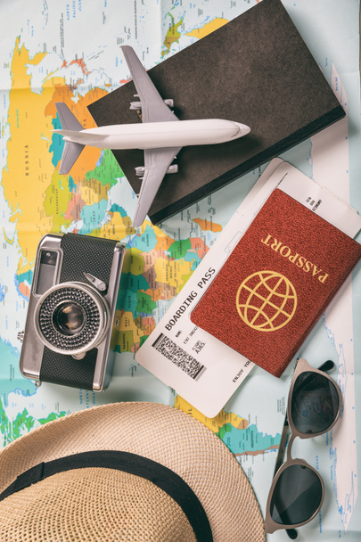Utazási és nyaralási kiegészítők, térkép háttér. Utazás a turizmusra, üzlet a lényeges dolgokkal, jegyek, útlevél, könyv, kamera, szemüveg, kalap. Függőleges, felülnézet. - Fotó, kép