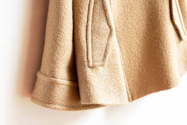 beige wool coat hanging on clothes hanger on white background.Close up. - Фото, зображення