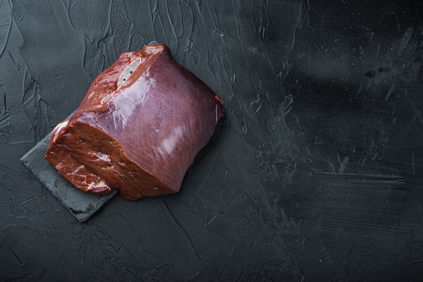 Raw beef liver on black background, flat lay with copy space. - Zdjęcie, obraz