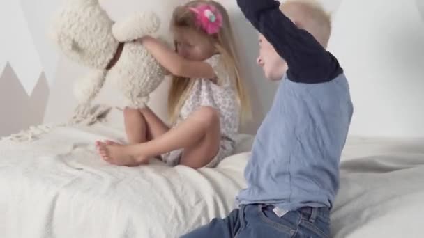 Grappige kinderen spelen thuis met teddyberen op het bed - Video
