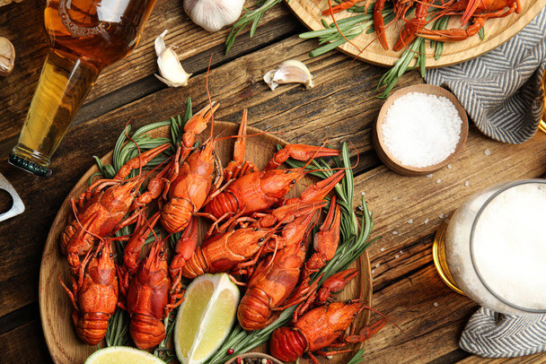 Flat lay composition with delicious red boiled crayfishes and beer on wooden table - Foto, Imagem