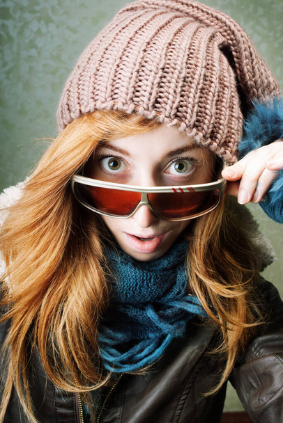 Überraschtes Mädchen in Winterkleidung zieht Sonnenbrille herunter - Foto, Bild
