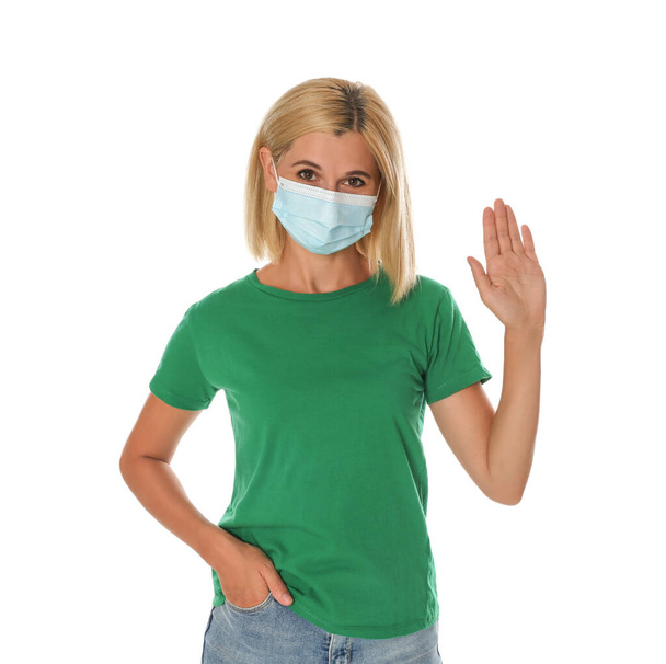 Woman in protective mask showing hello gesture on white background. Keeping social distance during coronavirus pandemic - Photo, image