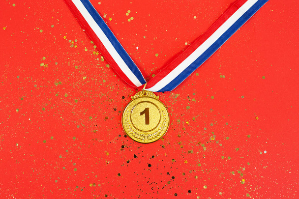 Médaille d'or 1 place avec un ruban sur fond de paillettes rouges. concept pour gagner ou réussir, concept de récompense - Photo, image