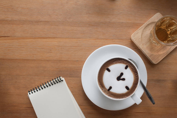 Close up di una tazza di caffellatte caldo art ha disegnato un concetto di business oclock su tavolo in legno con taccuino. - Foto, immagini