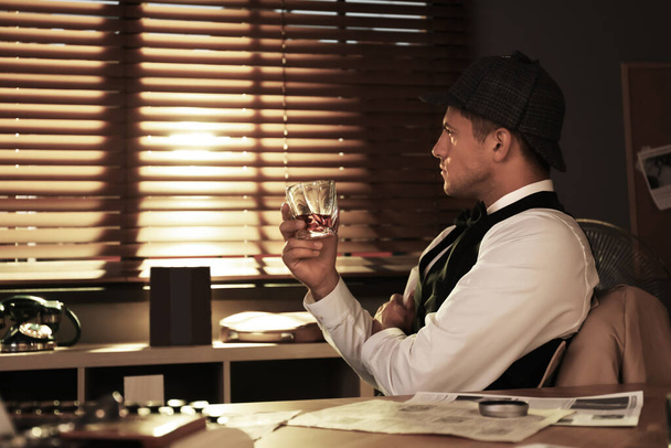Old fashioned detective with drink at table in office - Фото, зображення
