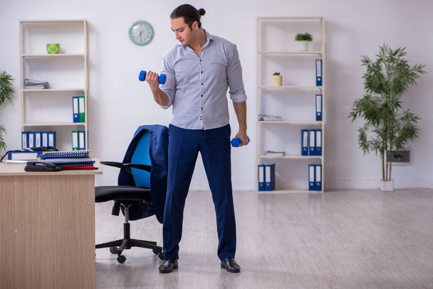 Молодий красивий чоловік працівник робить вправи в офісі
 - Фото, зображення