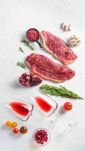 Steak de bœuf Picanha avec verres de vin rouge, romarin et grenade vue de dessus sur fond blanc texturé. Grande taille. - Photo, image