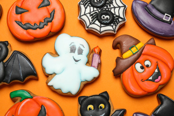 Different decorated gingerbread cookies on orange background, flat lay. Halloween celebration - Фото, изображение