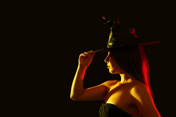 Young woman wearing witch costume on black background, space for text. Halloween party - Foto, Imagem