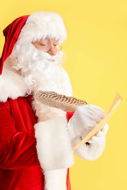 Weihnachtsmann macht Liste der Geschenke auf farbigem Hintergrund - Foto, Bild