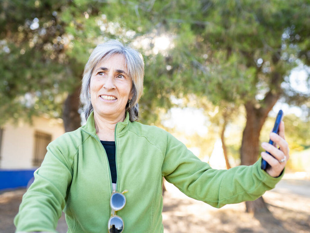 старша жінка в парку за допомогою смартфона і велосипеда
 - Фото, зображення