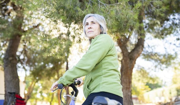 mujer mayor con una bicicleta en el parque - Foto, Imagen