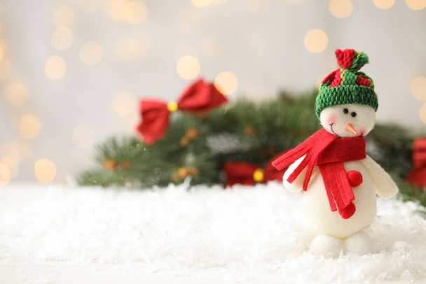 Snowman toy on snow against blurred festive lights, space for text. Christmas decoration - Foto, imagen