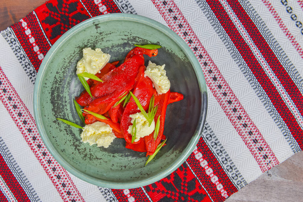 Baked pepper Salad with feta cheese, vegetable salad served in a bowl over traditional Ukrainian tablecloth. Delicious veggies salad. - Φωτογραφία, εικόνα