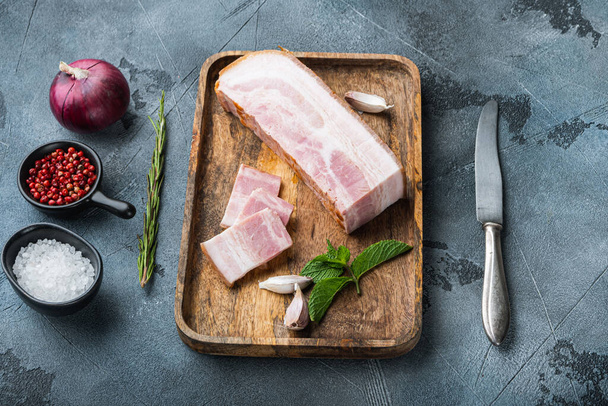 Bacon pancetta cut and sliced with herbs on grey textured background. - Foto, Imagen