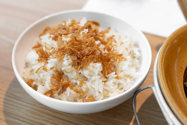 Höyrytetty riisi paistettua salottisipulia, tarjoillaan valkoinen kulho.  - Valokuva, kuva