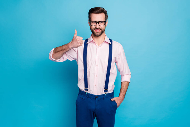 Photo of handsome macho business man trend clothes guy toothy smile eyesight vision specs raise thumb up express agreement wear pink shirt suspenders pants isolated blue color background - Fotoğraf, Görsel