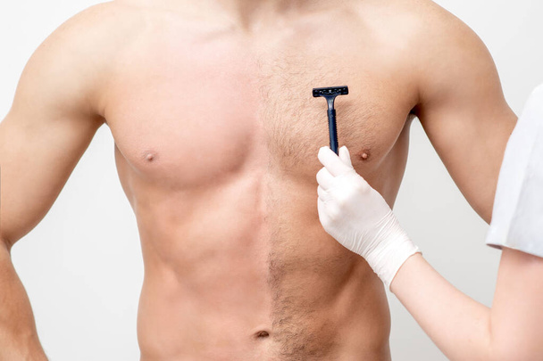 Hand of female beautician shaves chest of young man by razor. Concept of hair removal - Fotoğraf, Görsel