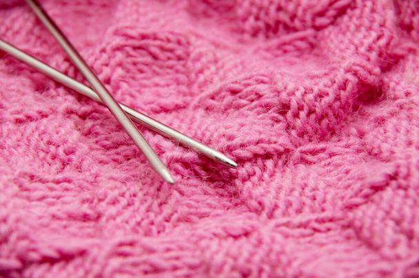 Yksityiskohta kudotut käsityö neuloa villaa suunnittelu rakenne ja neulonta neula. Kangas vaaleanpunainen tausta - Valokuva, kuva