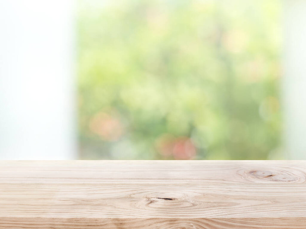 Tampo de mesa de madeira vazio no jardim verde abstrato borrão da visão da janela pela manhã. Para exibição de produto de montagem ou layout visual de chave de design - Foto, Imagem