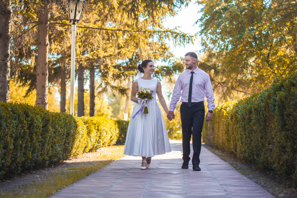 happy bride and groom are walking in the green park - Valokuva, kuva