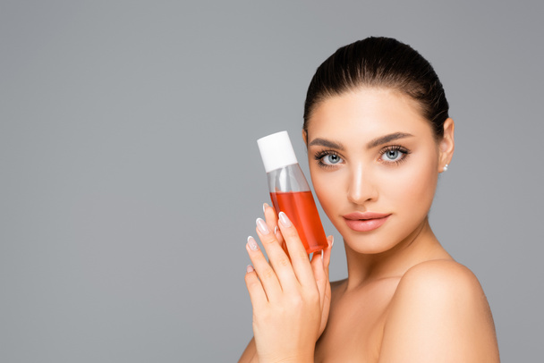 beautiful woman with bottle of lotion isolated on grey - Fotoğraf, Görsel