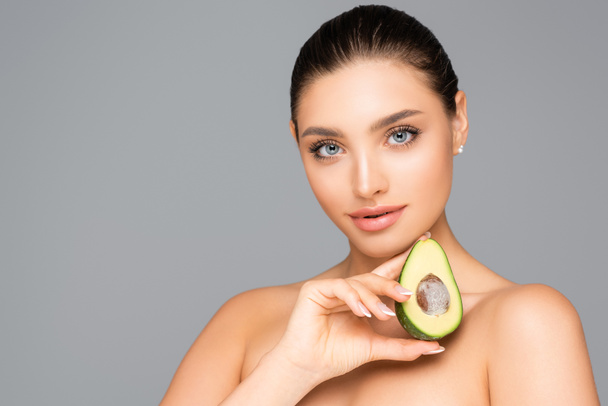 woman with naked shoulders and avocado half isolated on grey - Foto, imagen