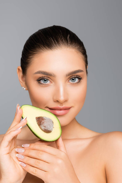 woman with naked shoulders and avocado half isolated on grey - Fotó, kép