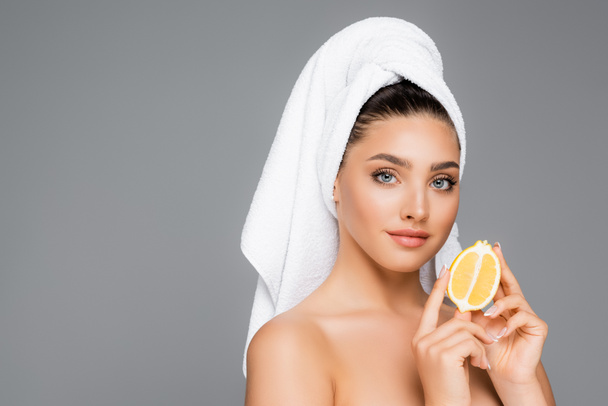 vrouw met handdoek op hoofd en citroen geïsoleerd op grijs - Foto, afbeelding