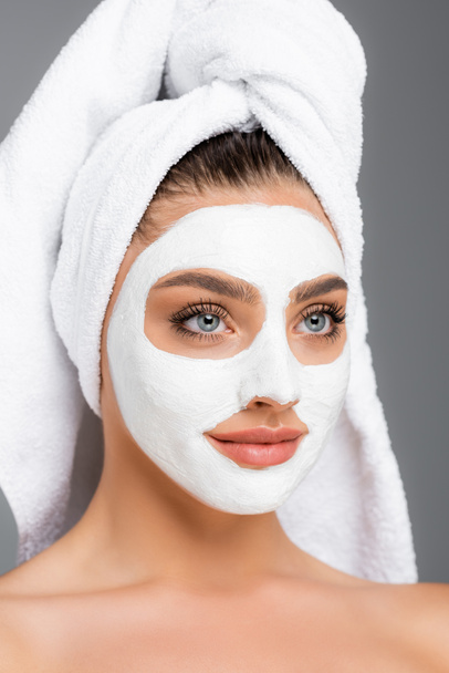 woman with towel on head and clay mask on face isolated on grey - Photo, Image
