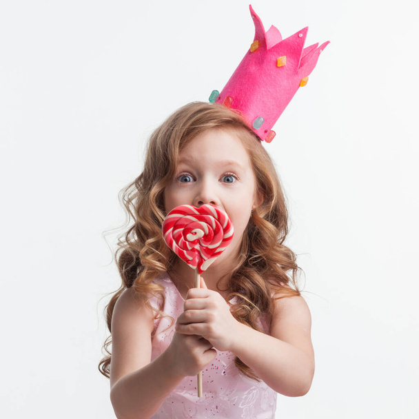 Beautiful little candy princess girl in crown with big pink heart lollipop - Fotografie, Obrázek