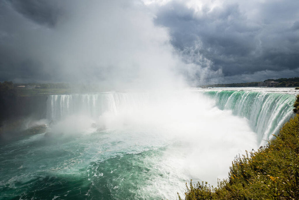 Blick auf die Niagarafälle von der kanadischen Seite. Bewölktes, aber sonniges Wetter, grünes Wasser. - Foto, Bild