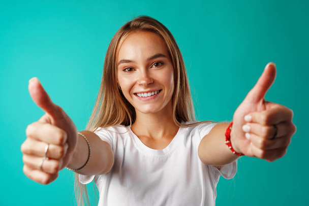 Portrait of a cheerful young woman showing thumbs up sign - Foto, afbeelding